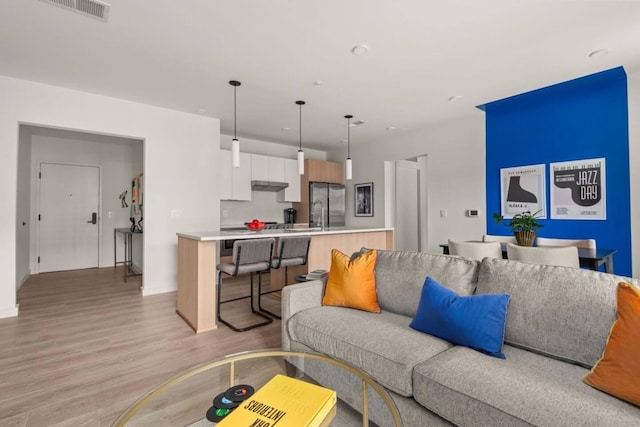 living room featuring light wood-style floors, baseboards, and visible vents