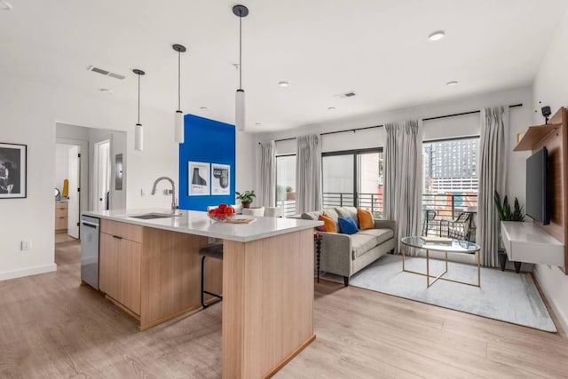 kitchen featuring an island with sink, modern cabinets, open floor plan, hanging light fixtures, and a sink