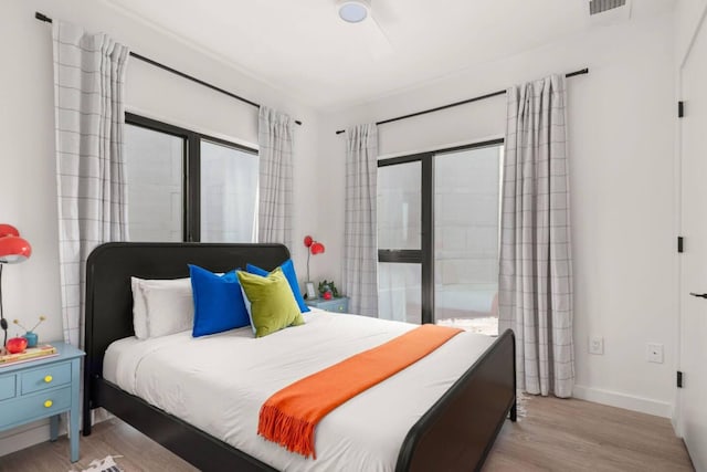 bedroom with light wood-style flooring, visible vents, and baseboards