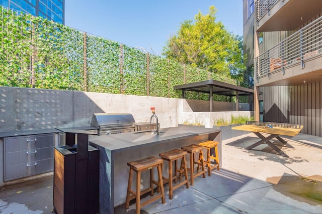 view of patio / terrace with area for grilling, a bar, an outdoor kitchen, and a sink