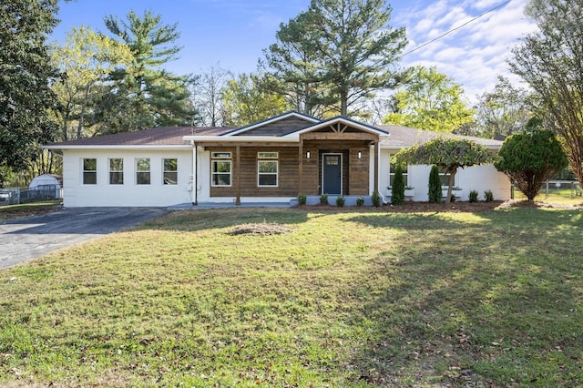 ranch-style house featuring covered porch and a front lawn