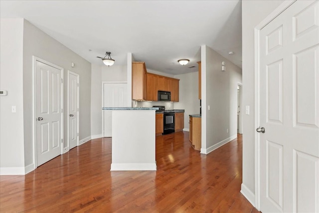 kitchen with black appliances, dark countertops, wood finished floors, and baseboards