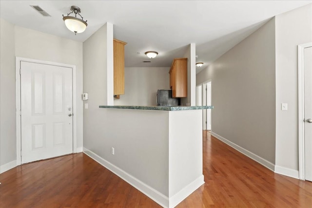 kitchen featuring baseboards, wood finished floors, and freestanding refrigerator