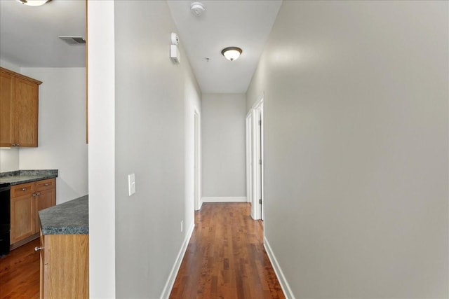 corridor with visible vents, dark wood-type flooring, and baseboards