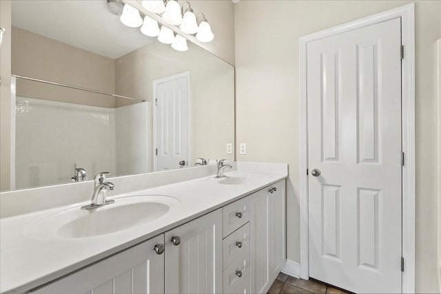 bathroom with double vanity, a shower, tile patterned floors, and a sink