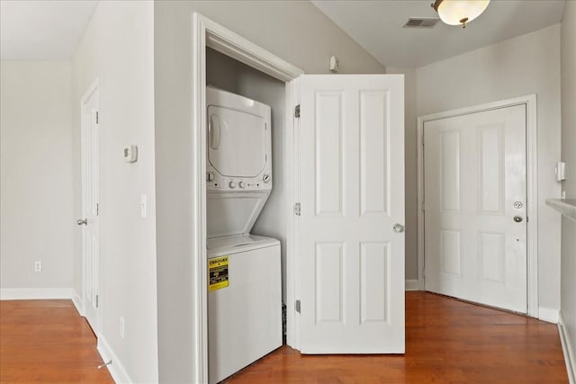 laundry area featuring wood finished floors, visible vents, baseboards, laundry area, and stacked washer and dryer