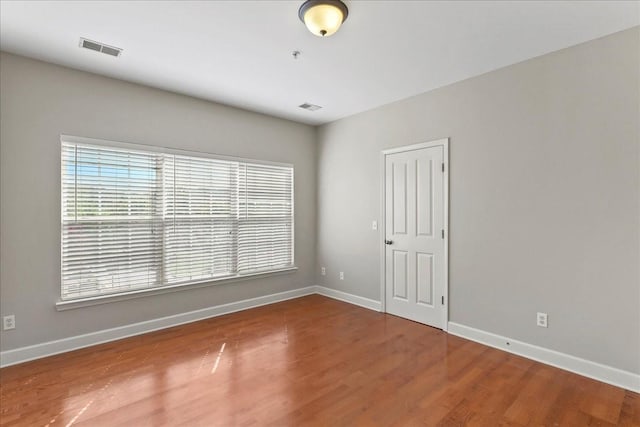 spare room featuring visible vents, baseboards, and wood finished floors