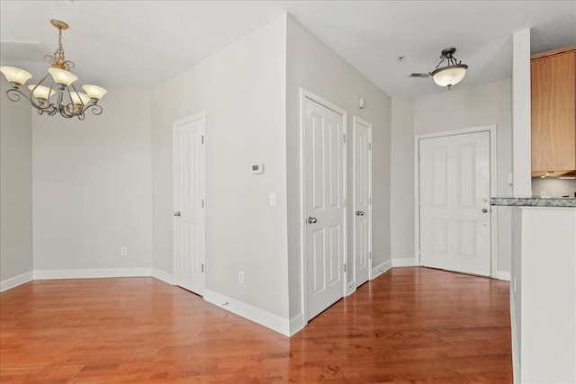 interior space with a notable chandelier, wood finished floors, and baseboards