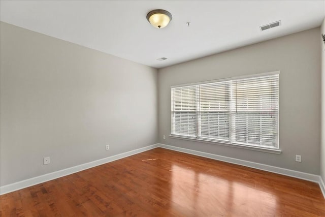 empty room featuring visible vents, baseboards, and wood finished floors