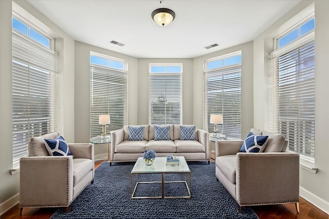 living area featuring visible vents, plenty of natural light, baseboards, and wood finished floors