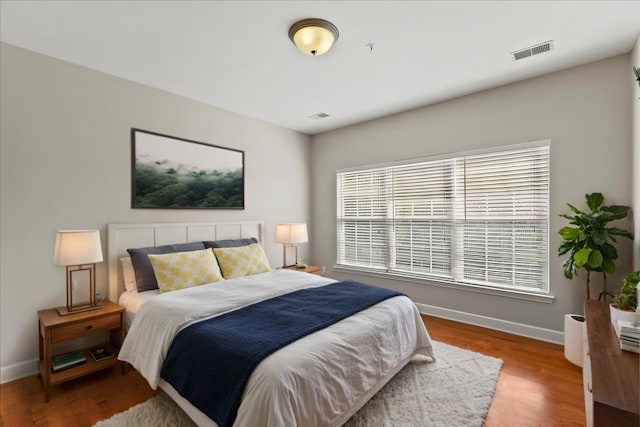 bedroom with visible vents, baseboards, and wood finished floors