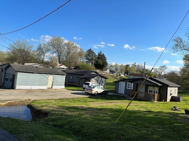 view of front of home with a garage, covered porch, an outdoor structure, and a front yard