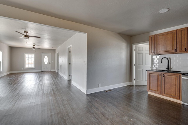 kitchen with dark wood-style flooring, a sink, open floor plan, brown cabinets, and dark countertops