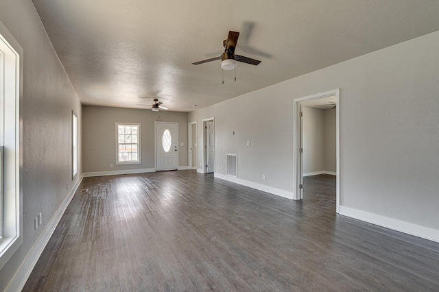 unfurnished living room with ceiling fan, dark wood-style flooring, visible vents, and baseboards