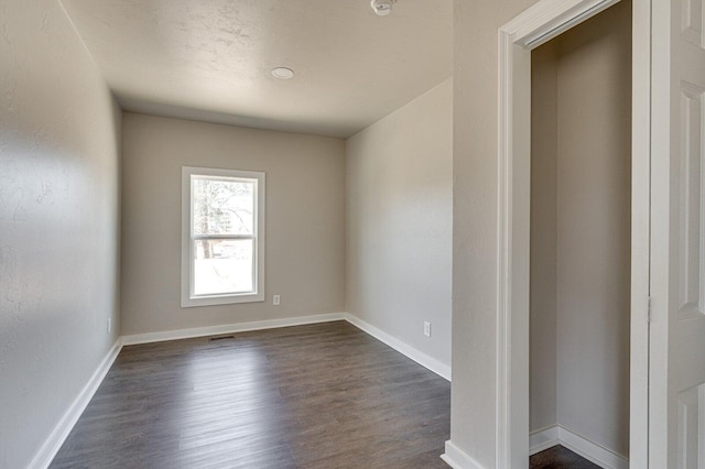 unfurnished room with dark wood-type flooring and baseboards