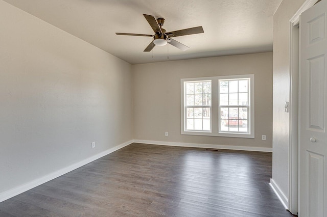 spare room with visible vents, dark wood finished floors, baseboards, and ceiling fan