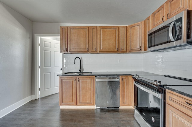 kitchen featuring dark countertops, dark wood-style floors, stainless steel appliances, and a sink