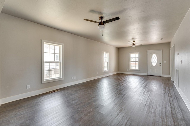 interior space featuring baseboards, a textured ceiling, visible vents, and dark wood-style flooring