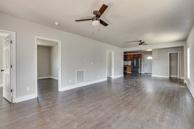 unfurnished living room with baseboards, dark wood finished floors, visible vents, and a ceiling fan