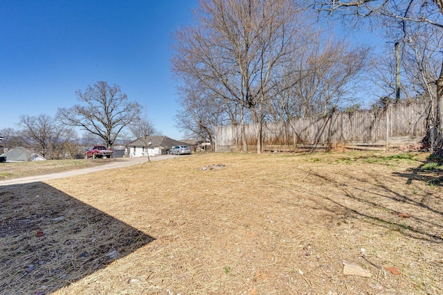 view of yard featuring a garage, driveway, and fence