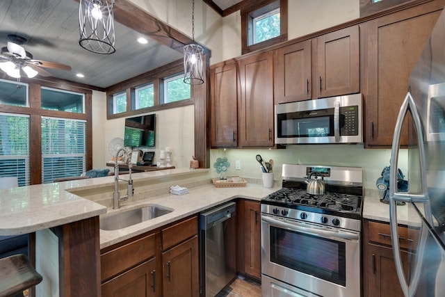 kitchen featuring a breakfast bar area, stainless steel appliances, a peninsula, hanging light fixtures, and light stone countertops