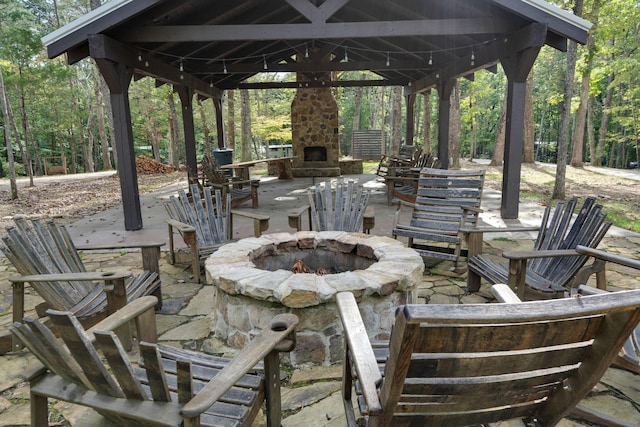 view of patio / terrace with an outdoor fire pit, an outdoor stone fireplace, and a gazebo