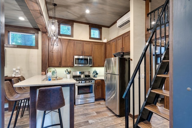 kitchen featuring light wood-style flooring, brown cabinets, decorative light fixtures, stainless steel appliances, and light countertops