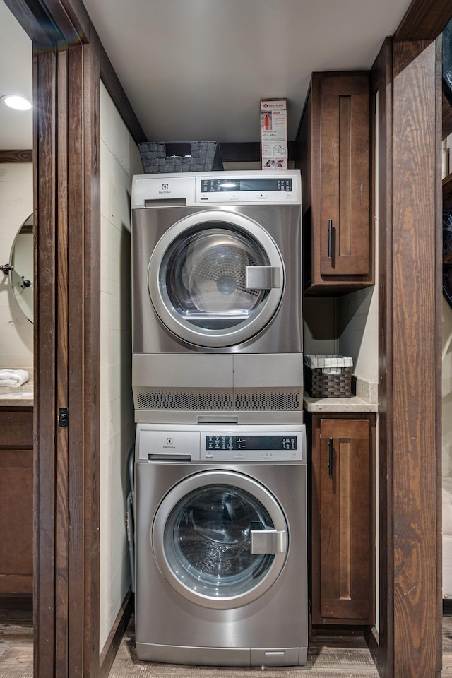 laundry room with cabinet space and stacked washer and clothes dryer