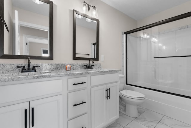 bathroom featuring marble finish floor, a sink, toilet, and double vanity