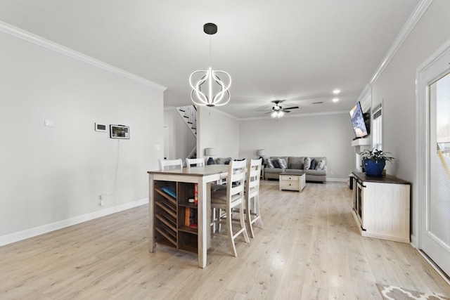 dining room with ceiling fan with notable chandelier, baseboards, light wood-style floors, ornamental molding, and stairway