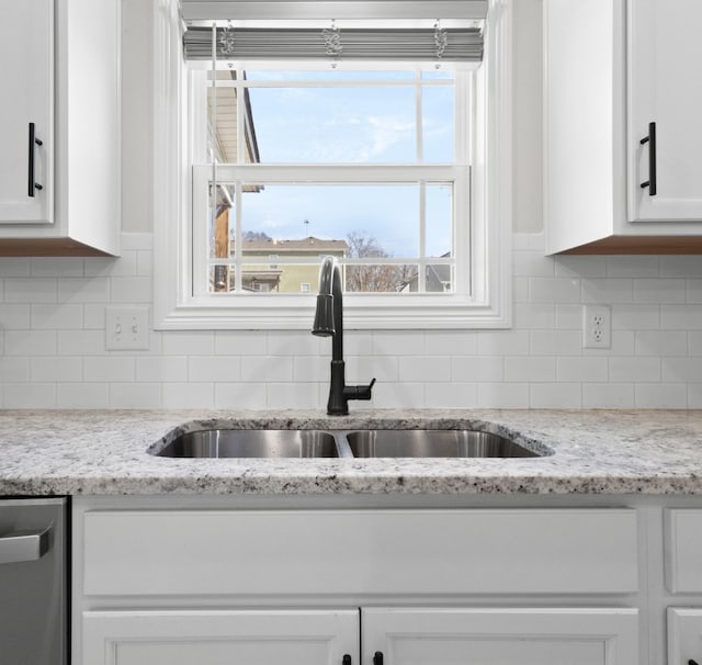 kitchen with a sink, white cabinetry, decorative backsplash, and stainless steel dishwasher