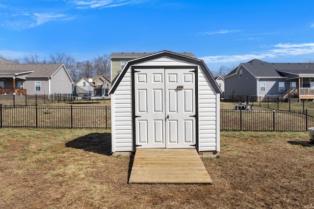 view of shed with a trampoline, a fenced backyard, and a residential view