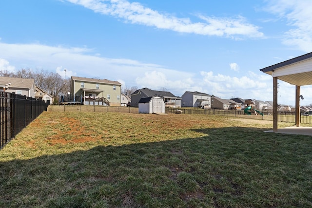 view of yard with playground community, a storage unit, a fenced backyard, and a residential view