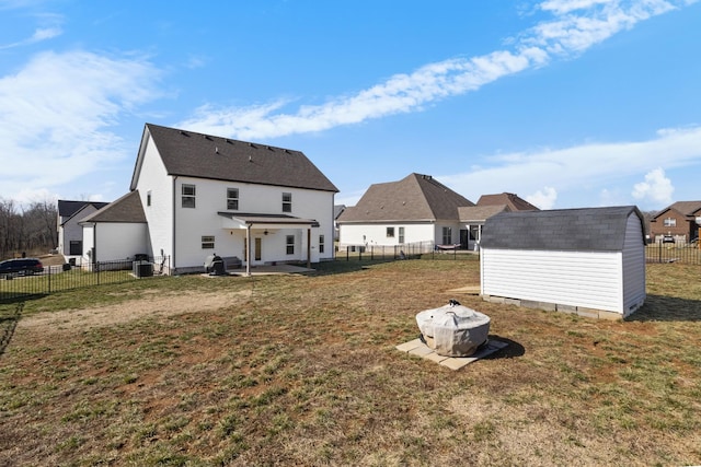 rear view of house featuring a storage shed, a yard, an outdoor structure, and a fenced backyard