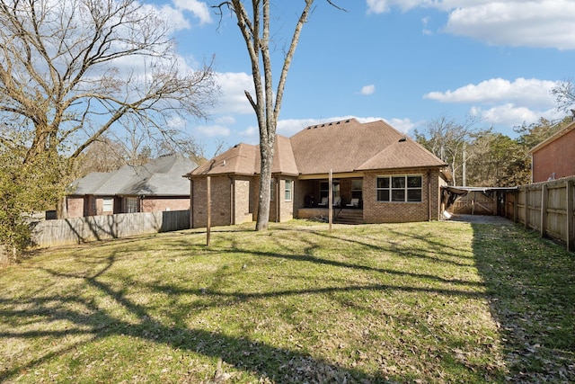 rear view of house with a yard, brick siding, roof with shingles, and a fenced backyard