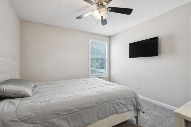 carpeted bedroom with ceiling fan, a textured ceiling, and baseboards