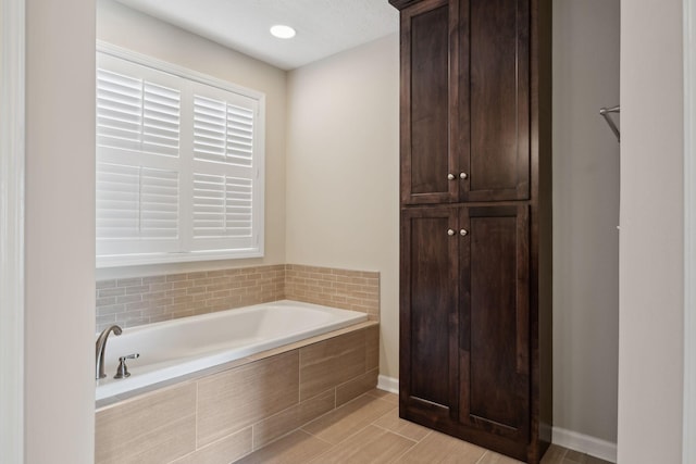 bathroom featuring baseboards and a bath