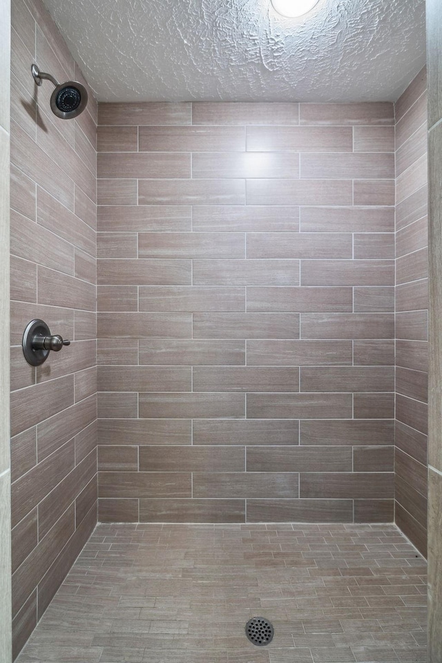 full bathroom with a tile shower and a textured ceiling