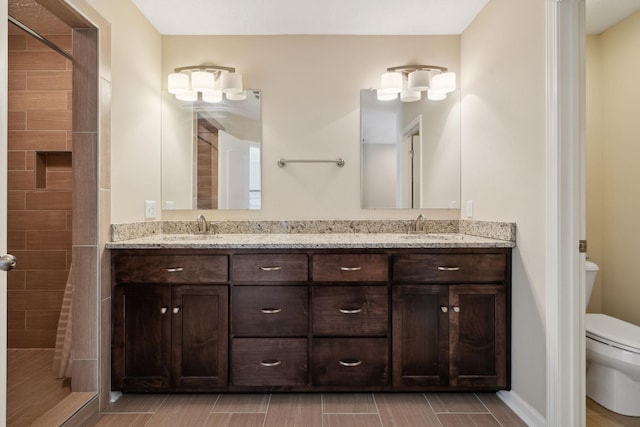 bathroom featuring toilet, wood tiled floor, double vanity, and a sink