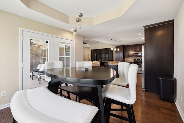 dining space featuring a tray ceiling, dark wood-style flooring, french doors, and baseboards