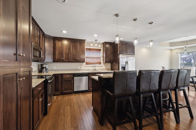 kitchen featuring a kitchen breakfast bar, appliances with stainless steel finishes, a center island, and pendant lighting