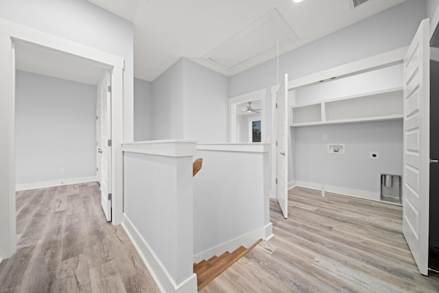 corridor with light wood-style flooring, an upstairs landing, attic access, and baseboards