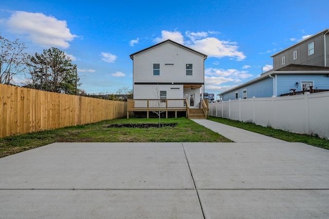 rear view of house featuring a deck, a lawn, and a fenced backyard