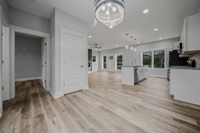 kitchen with pendant lighting, light wood finished floors, open floor plan, white cabinets, and dishwasher