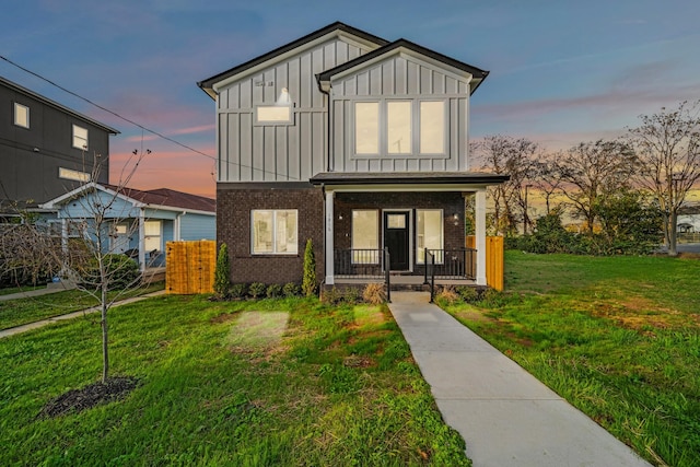 view of front of property with a porch, board and batten siding, a front lawn, and brick siding