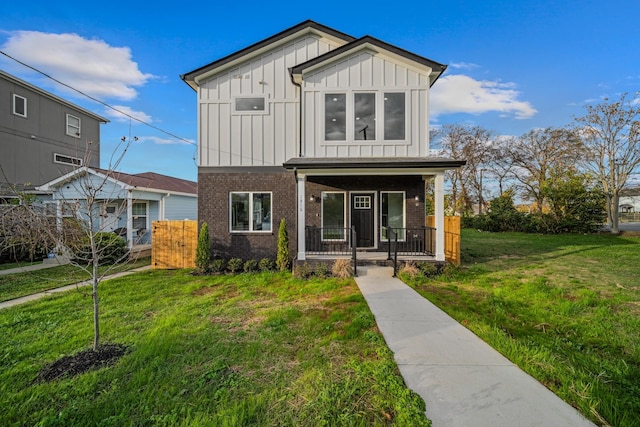 view of front facade with covered porch, a front yard, board and batten siding, and brick siding