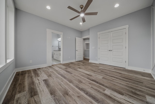 unfurnished bedroom featuring a closet, recessed lighting, wood finished floors, and baseboards