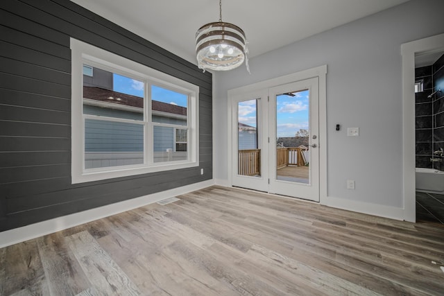 interior space featuring a notable chandelier, plenty of natural light, visible vents, and wood finished floors