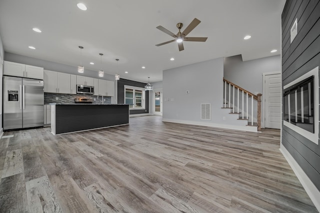 kitchen featuring visible vents, open floor plan, a center island, stainless steel appliances, and white cabinetry