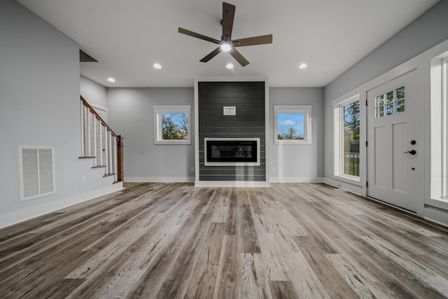 unfurnished living room with a fireplace, recessed lighting, visible vents, stairway, and light wood-type flooring